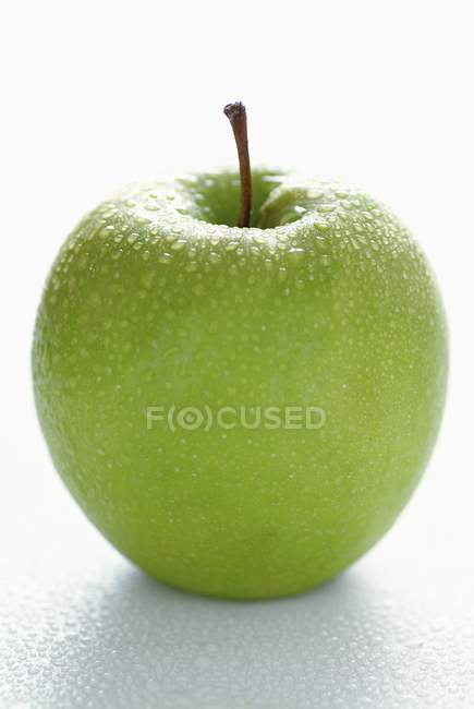 Зеленое яблоко с каплями воды — стоковое фото