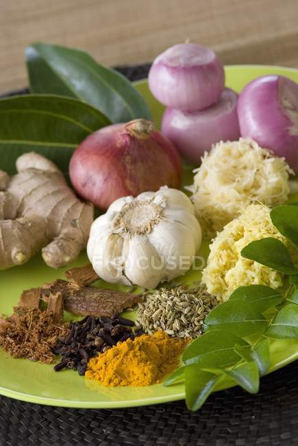 Selection of herbs and spices on green plate — Stock Photo