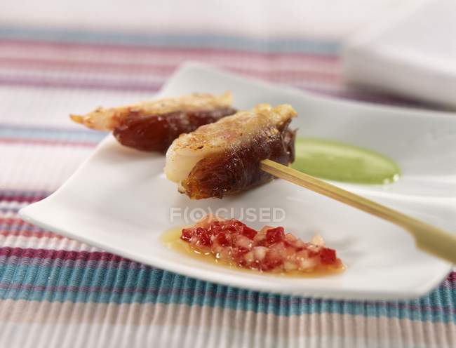 Closeup view of lobster meat on skewer with sauces on square saucer — Stock Photo