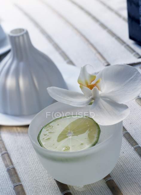 Closeup view of drink with lime slice and flower — Stock Photo