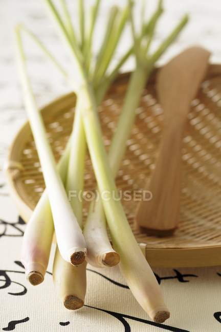 Крупный план свежей цитронеллы на деревянной тарелке и ноже — стоковое фото