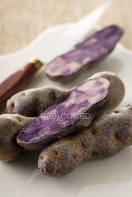 Vitelotte patatas con mitades - foto de stock