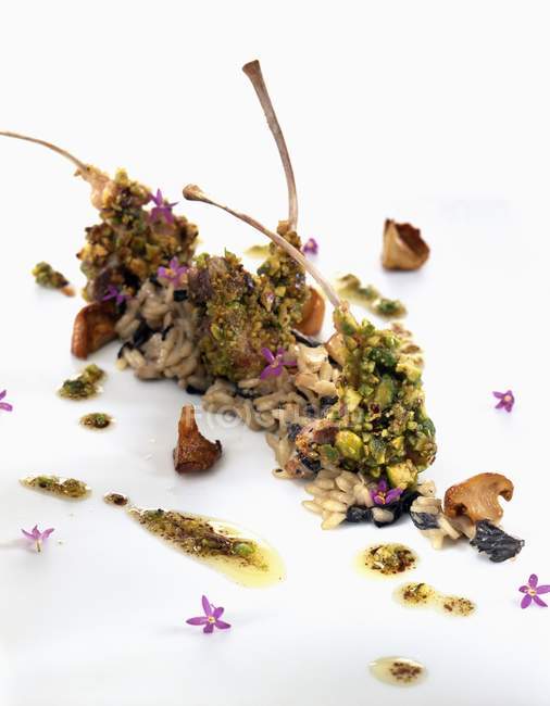 Closeup view of meat cutlets with mushrooms, pistachio nuts and flowers on white surface — Stock Photo