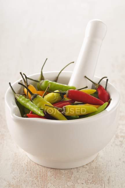 Pimentos in a mortar over light surface — Stock Photo