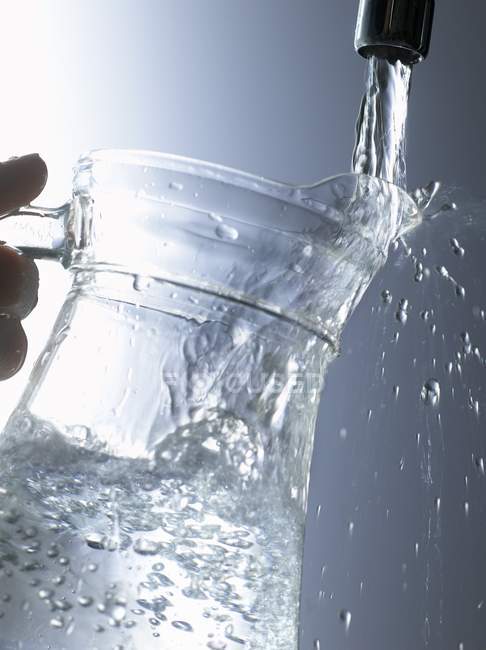Vista close-up de encher um jarro de água sob a torneira — Fotografia de Stock