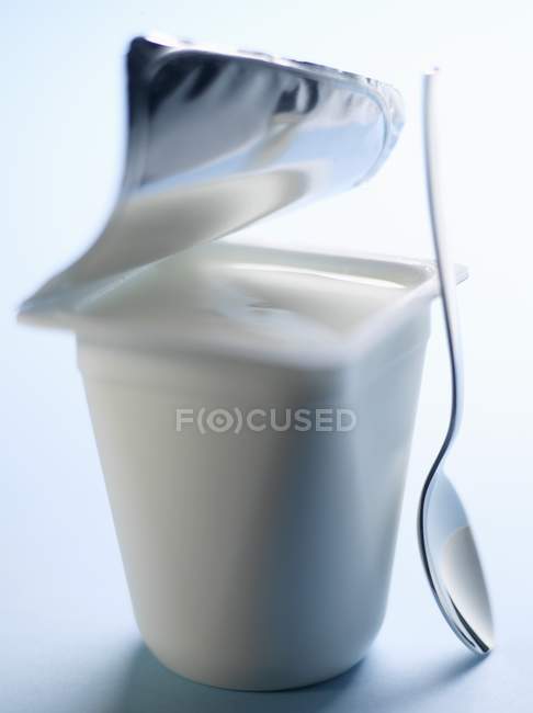Panela aberta de iogurte com colher — Fotografia de Stock