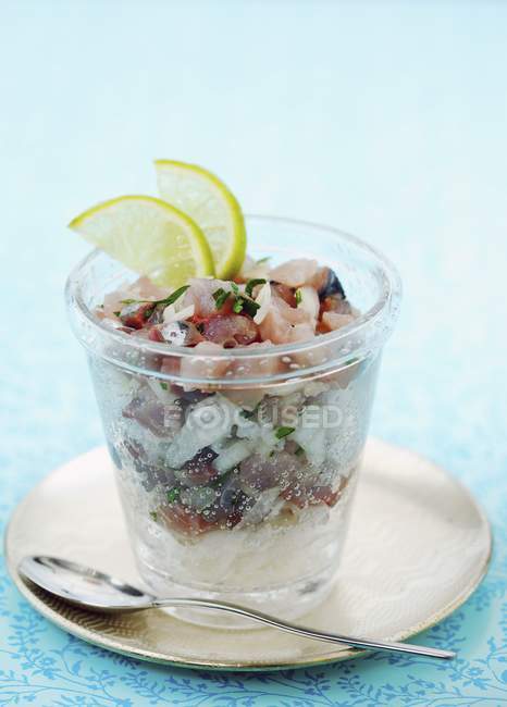 Mackerel tartare in glass over plate with spoon — Stock Photo