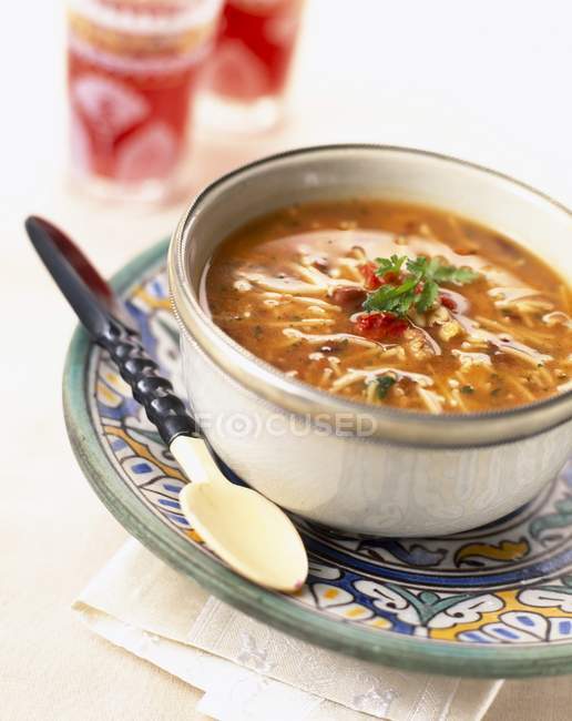 Nahaufnahme der marokkanischen Chorba-Suppe im Topf mit Löffel auf gemustertem Teller — Stockfoto