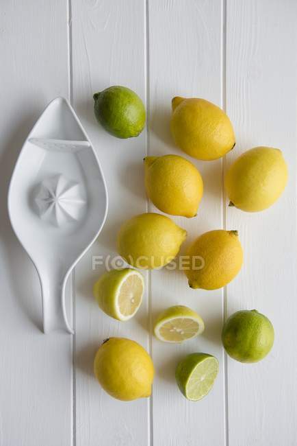 Citrons et citrons verts avec presse-agrumes en céramique — Photo de stock