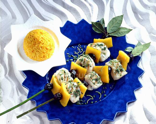 Monk fish skewers with herbs over blue plate — Stock Photo