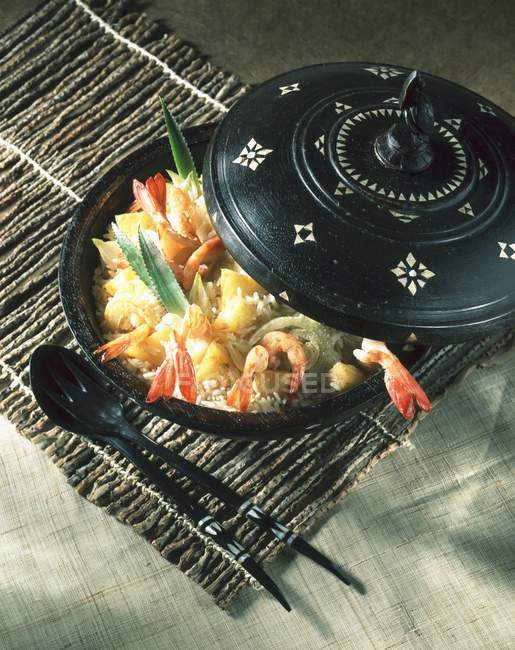 Shrimp pilaf from the islands in black pot over straw mat — Stock Photo