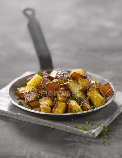 Vue rapprochée des dés de pommes de terre frites avec des herbes sur une petite casserole — Photo de stock