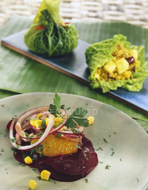 Verdure e anelli di cipolla su piatto bianco sopra tavolo — Foto stock