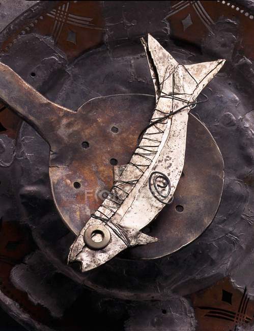 Elevated view of fish shaped figure on an old skimmer over plate — Stock Photo