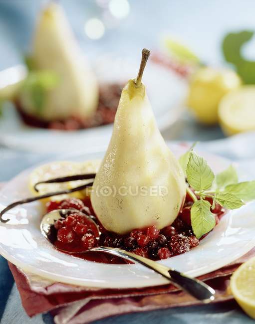 Primo piano vista di pera alla vaniglia al vapore su bacche stufate — Foto stock