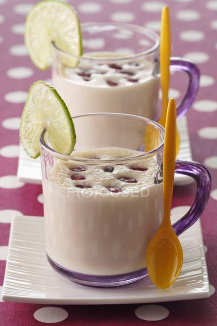 Coconut soup with pomegranate seeds in cups with spoons — Stock Photo