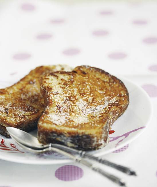 Французские тосты на белой тарелке с ложками — стоковое фото