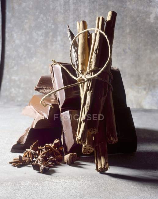 Chocolate and tied cinnamon sticks — Stock Photo