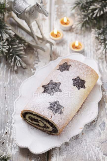 Closeup view of poppy roll with icing sugar and burning candles — Stock Photo