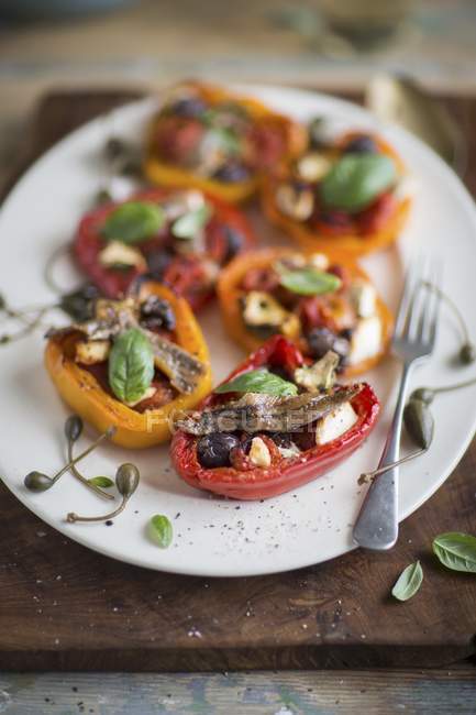 Stuffed pepper halves with anchovies, olives and capers on white plate  with fork — Stock Photo