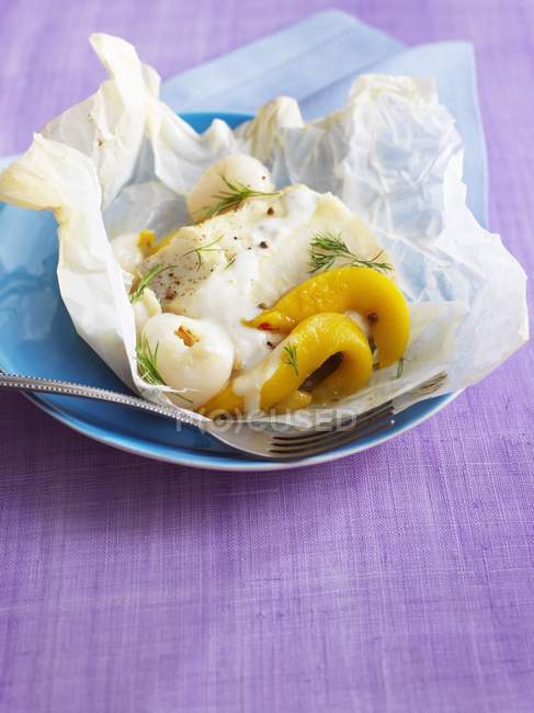 Cod with exotic fruit in wax paper — Stock Photo