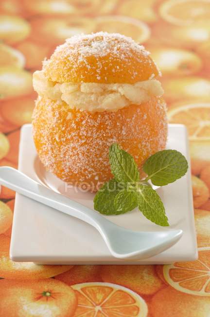 Closeup view of iced orange with mint leaves and spoon on plate — Stock Photo