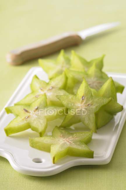 Aufgeschnittene Sternfrucht auf weißem Schreibtisch über grüner Oberfläche mit Messer — Stockfoto