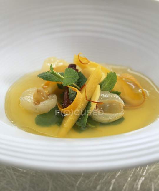 Closeup view of soup with mango, lychees and mint leaves — Stock Photo