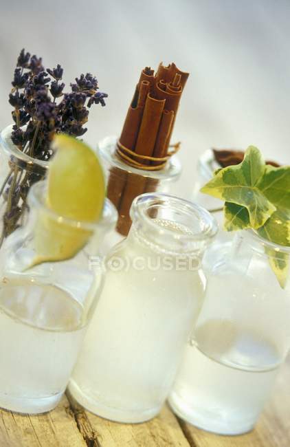 Closeup view of refreshing drinks with lavender, lime slice, cinnamon sticks and leaves in bottles — Stock Photo
