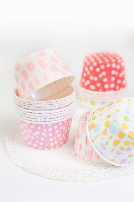 Vue rapprochée de tasses pointillées colorées en piles sur napperon et surface blanche — Photo de stock