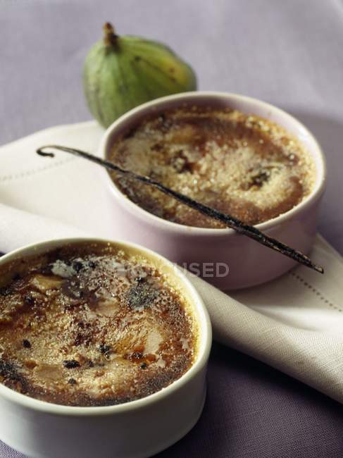 Fig and vanilla Crme brle in white pots over towel — Stock Photo
