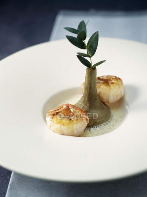 Pan-fried Dublin Bay prawns and poivrade artichoke with eucalyptus broth on white plate — Stock Photo