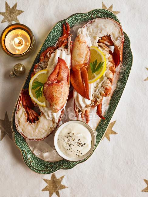 Top view of lobster halves with mayonnaise, lemon slices and burning candle — Stock Photo