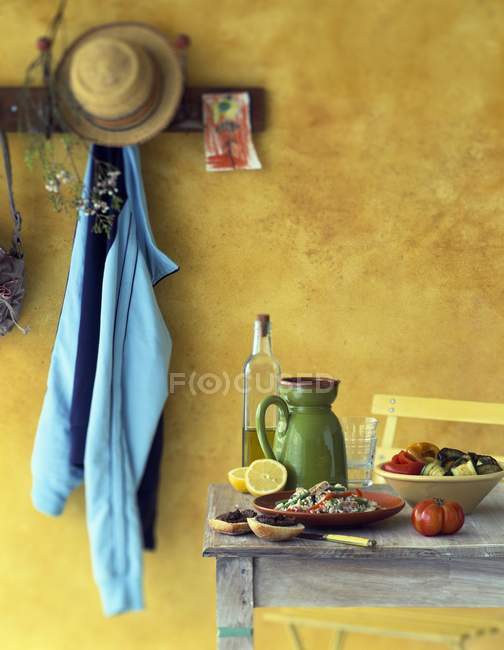 Almuerzo de verano al aire libre con mesa de madera contra pared amarilla - foto de stock