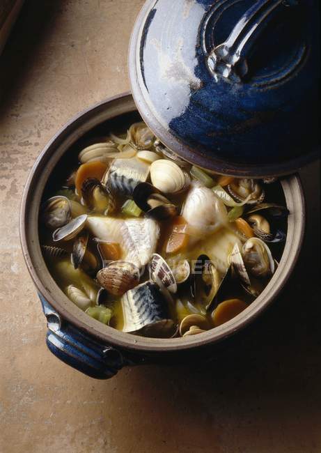 Fisherman soup in saucepan over wooden surface — Stock Photo