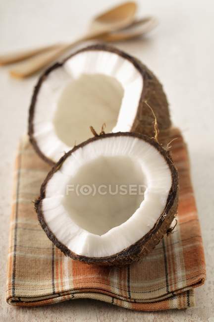 Coconuts halved over towel on table — Stock Photo