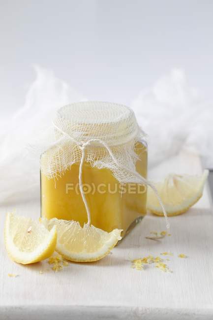Vista de cerca de la cuajada de limón en un frasco de vidrio con limones en rodajas - foto de stock