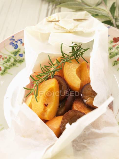 Closeup view of rosemary flavored peaches and plums cooked in wax paper — Stock Photo