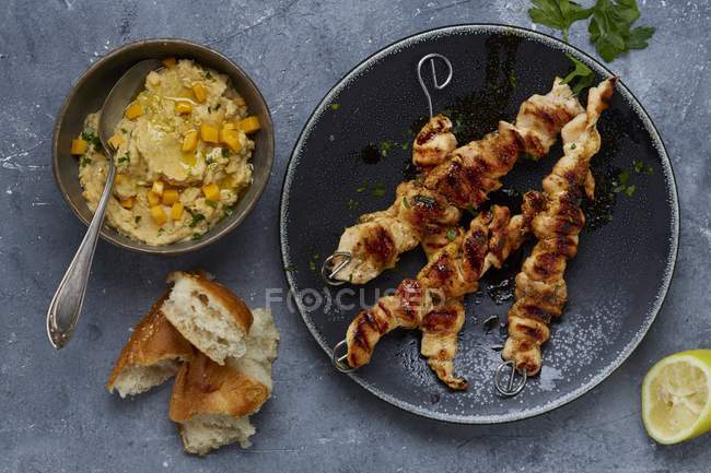 Pasteles de pollo con hummus en platos negros - foto de stock
