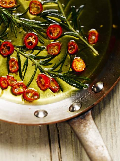 Chiliringe und Rosmarin in einer Pfanne mit Olivenöl — Stockfoto