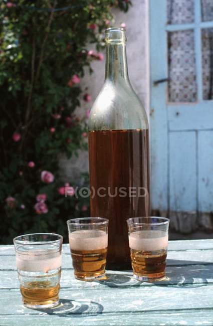 Visão diurna de cidra em garrafa e óculos na mesa de jardim — Fotografia de Stock