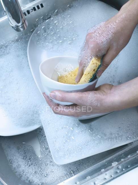 Vista elevada das mãos lavar os pratos na pia — Fotografia de Stock