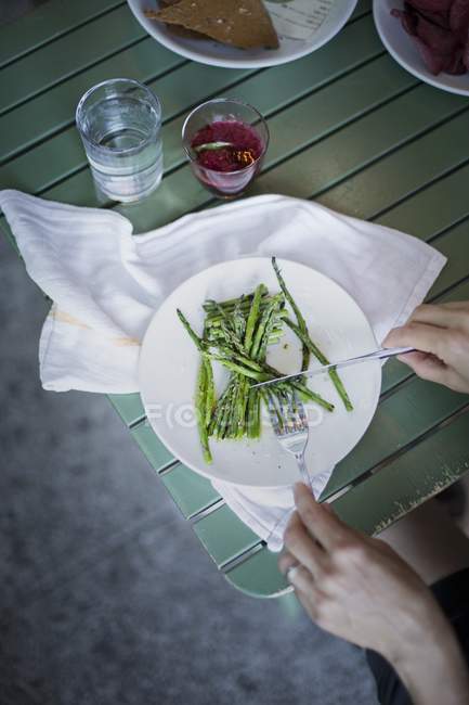 Mujer comiendo espárragos verdes blanqueados - foto de stock