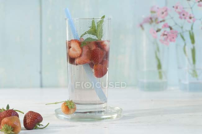 Vista de perto da água aromatizada com morangos e hortelã-pimenta num copo com palha — Fotografia de Stock