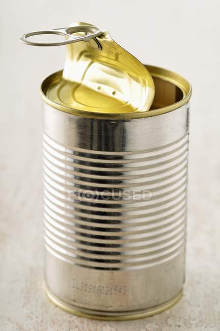 Vista close-up de uma lata aberta em uma superfície branca — Fotografia de Stock
