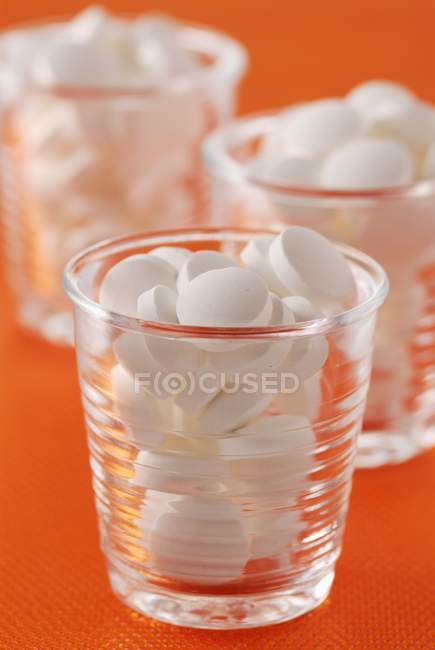 Vista close-up de óculos com pílulas brancas — Fotografia de Stock