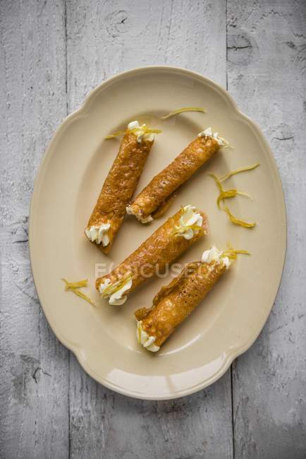 Верхний вид бренди Snap Tuilles с лимонным кремом на тарелке — стоковое фото