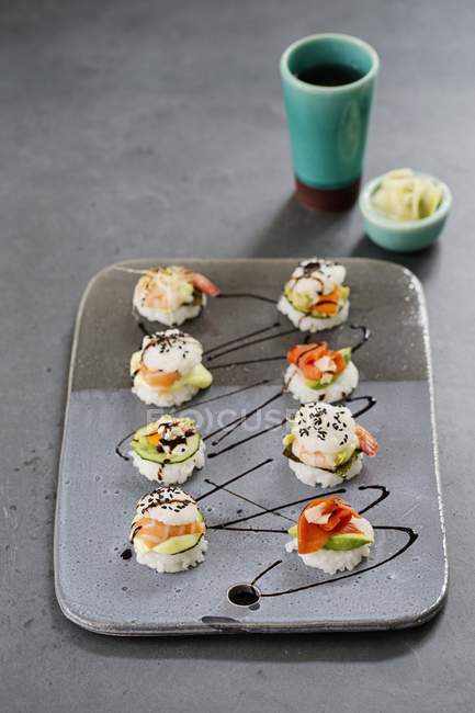 Восемь мини-суши-бургеров на керамической тарелке — стоковое фото