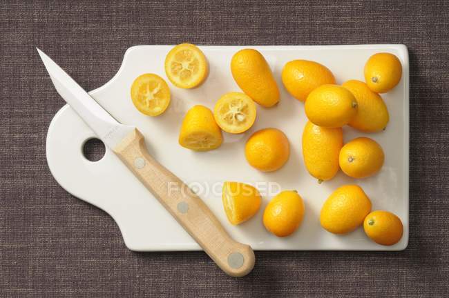 Kumquats frescos sobre tabla de cortar - foto de stock