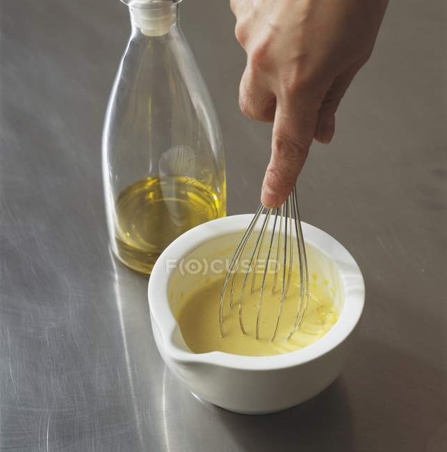 Closeup view of hand whipping oil with whisk — Stock Photo